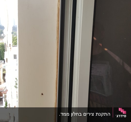 תריס פתוח עם מסגרת לבנה וחלון זכוכית